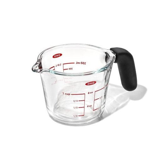 Clear glass measuring cup with bold measurement markings, dripless spout, and non-slip silicone handle for precise pouring.