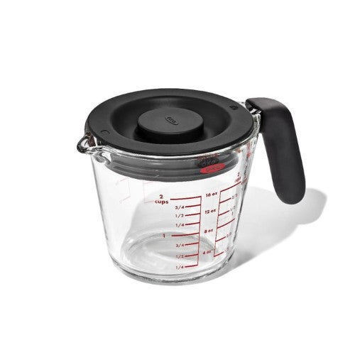 2-cup OXO Good Grips glass measuring cup with silicone lid, featuring clear markings and a non-slip handle for easy pouring and storage.