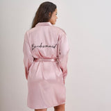 Pink satin bridesmaid dressing gown with black 'bridesmaid' embroidery, perfect for hen parties and bridal preparation.