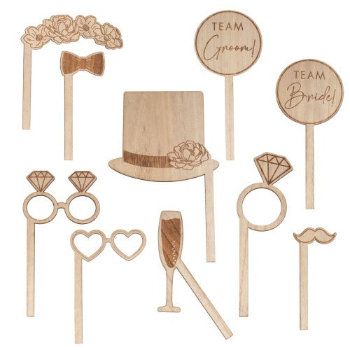 Rustic wooden wedding photo booth props with burnt details, including floral headband, heart glasses, and fun signs.