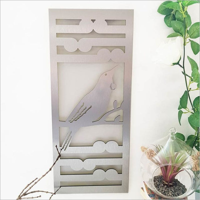 Brushed silver wall art panel featuring Tui and Koru, 55cm tall, ideal for indoor/outdoor decor.