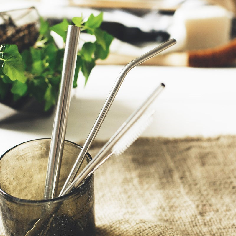Set of three reusable stainless steel straws in a cotton bag, including smoothie, angled, and straight straws with a cleaning brush.