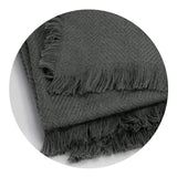 Luxurious charcoal throw blanket with herringbone design and fringe trim, crafted from eco-friendly polylana and acrylic blend.