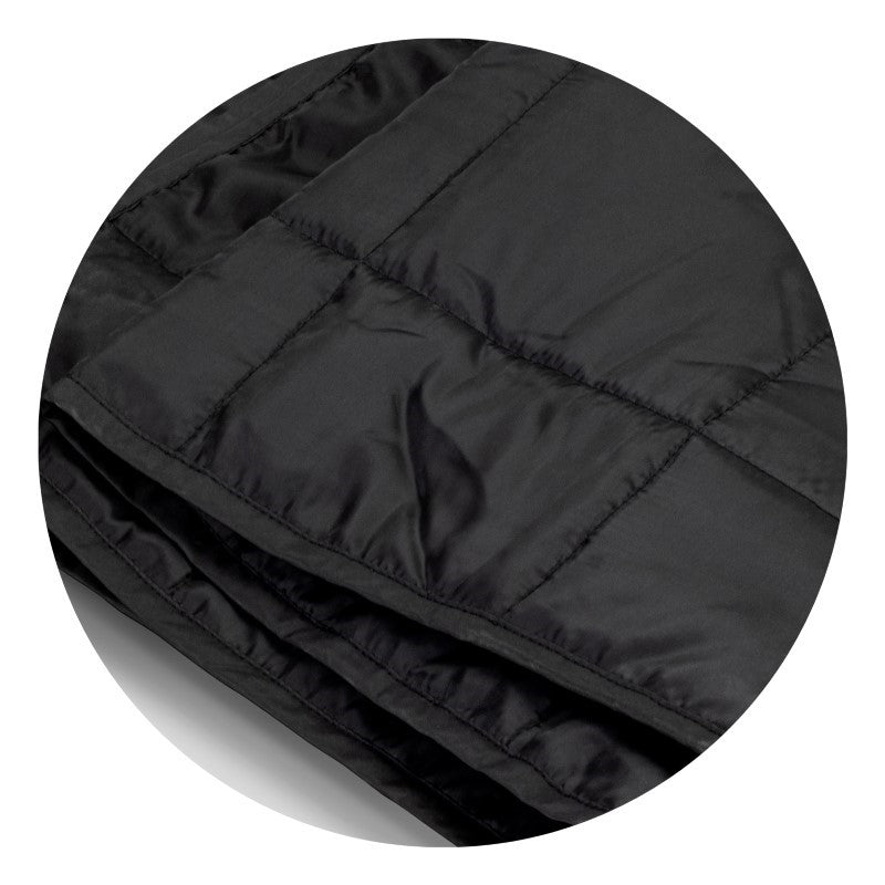Cozy black puffer blanket with water-resistant fabric, lightweight foam filling, and drawstring pouch for easy transport.