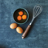 Elegantly designed black walnut whisk with stainless steel head, perfect for whipping and mixing ingredients in style.