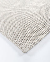 Handwoven beige rug, 250x350cm, with knotted weave; blends comfort and elegance for modern interiors.