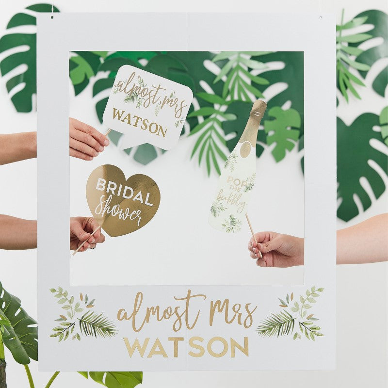 Customizable botanical photo booth frame for hen parties, featuring gold foil and personal message stickers.