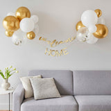 Gold and white balloon backdrop kit with 'Welcome' and 'Home' bunting, perfect for baby celebrations.