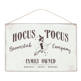 Retro metal sign featuring a pin-up witch illustration and 'Hocus Pocus Broomstick Company' text, ideal for Halloween decor.