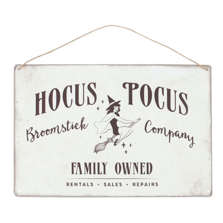 Retro metal sign featuring a pin-up witch illustration and 'Hocus Pocus Broomstick Company' text, ideal for Halloween decor.