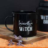 Enamel mug with "I'm Secretly A Witch" text on a black base, ideal for hot beverages and Halloween-themed decor.