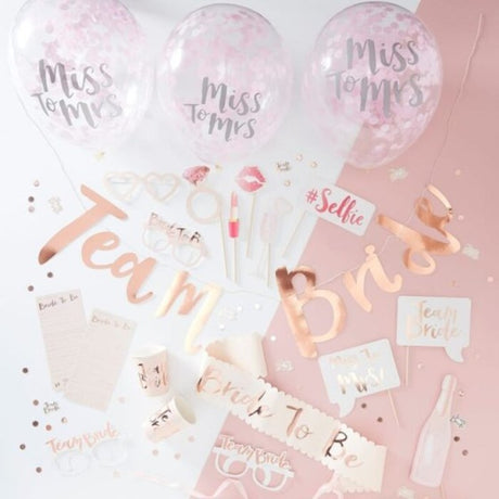 "Team Bride Party In A Box featuring rose gold foiled cups, fun glasses, props, balloons, and bunting for stylish hen celebrations."