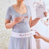 "Fun baby shower game with tummy tape for guessing baby bump size, includes scorecard and winner glass for celebrating guesses."