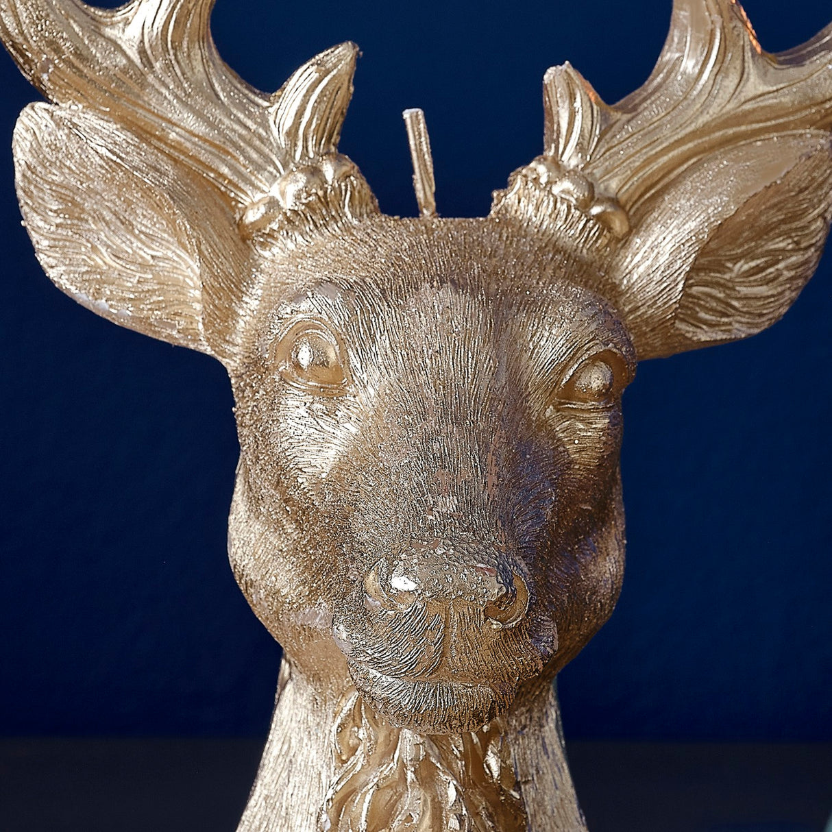 Gold stag candle casting a warm glow, perfect for festive decor and eco-friendly celebrations this holiday season.