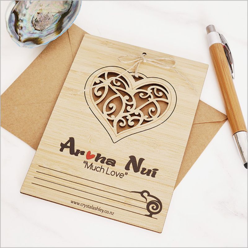 Bamboo postcard featuring Aroha Nui heart motif, eco-friendly, with jute string and envelope, ideal for heartfelt messages.