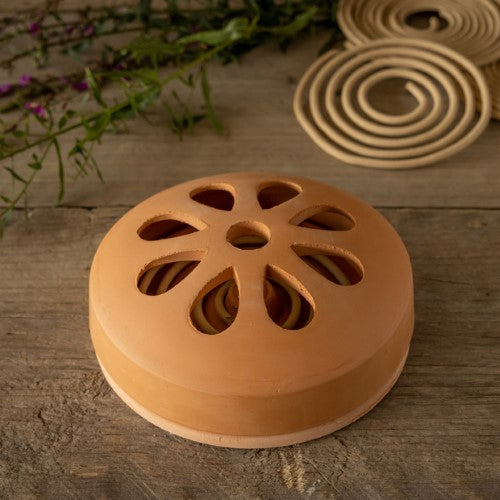 Citronella coils in a stylish terracotta holder, providing natural insect repellent for outdoor gatherings and summer nights.