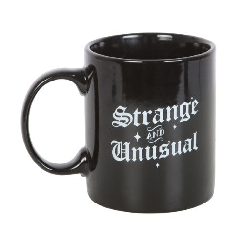 Ceramic mug with 'Strange and Unusual' in gothic script, perfect for hot beverages and showcasing your quirky style.