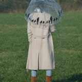 Transparent umbrella with whimsical birds-on-wire design, combining style and function for protection against rain and wind.