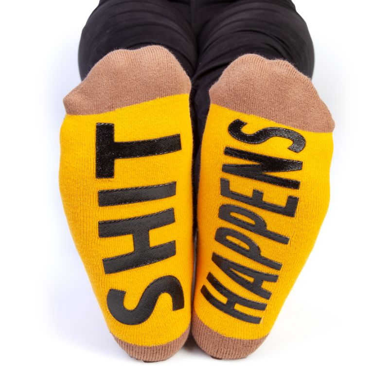 Whimsical socks featuring a Smiling Poo design on top and 'SHIT HAPPENS' on the soles, measuring 18cm. Perfect for fun and comfort!