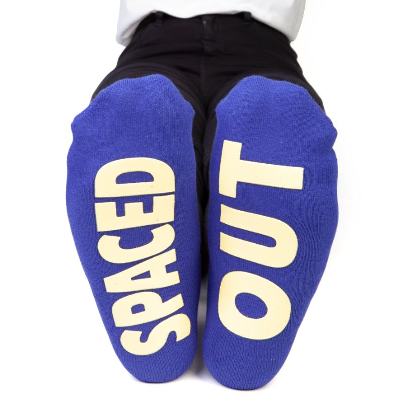 Vibrant socks featuring stars, planets, and "SPACED OUT" on the bottom, perfect for space enthusiasts and cozy wear.