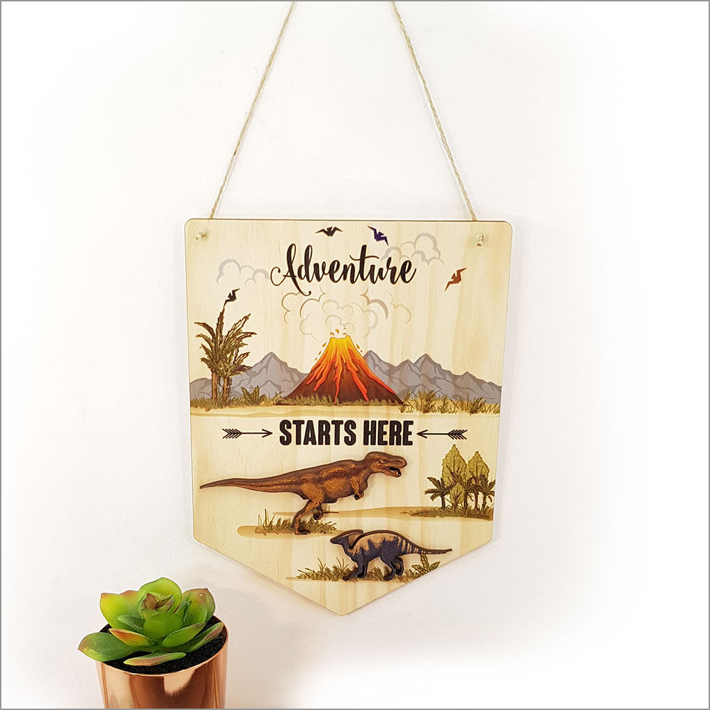 Eco-friendly pine wall art flag reading "Adventure Starts Here," perfect for inspiring wanderlust in any room.