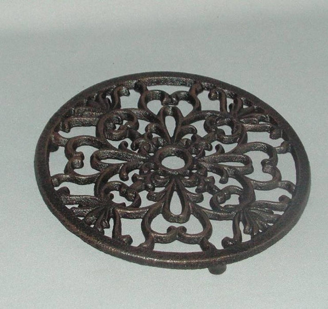 Decorative round cast iron trivet, 18cm, features intricate design, protects surfaces from hot dishes, adds elegance to kitchens.