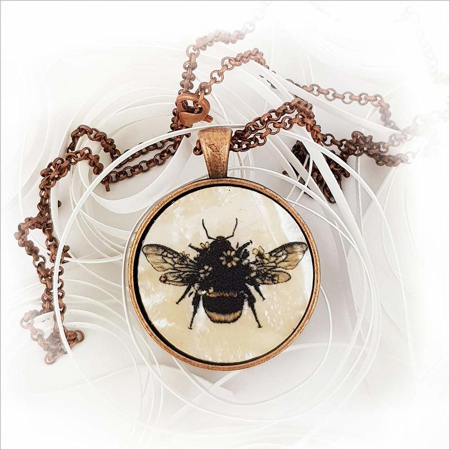 Circle necklace featuring floral bee design on mother of pearl, antique copper finish, and 75cm chain included.