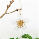 Laser-cut bamboo and white satin acrylic ornament shaped like a Manuka flower, perfect for holiday decor and gifting.