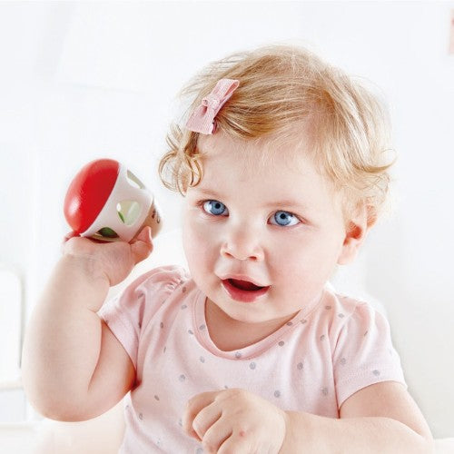 Wooden boomerang-shaped rattle for infants, features a gentle bell for auditory stimulation and easy grip for small hands.