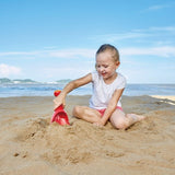 Bright red Hape Rain Shovel beach toy for children, perfect for sand and water play, with an ergonomic handle for easy grip.