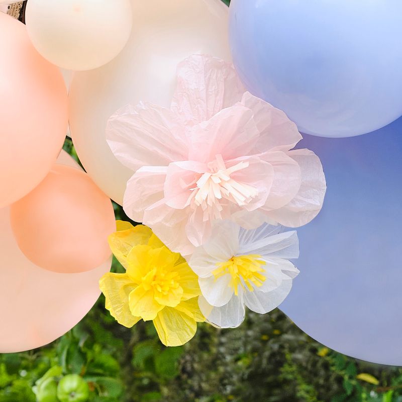 Pastel balloon arch featuring tissue paper flowers, perfect for elegant spring events and festive celebrations.