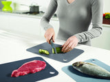 Colorful double-sided chopping mats by Joseph Joseph, featuring a knife-friendly surface and easy storage clips for hygiene and convenience.