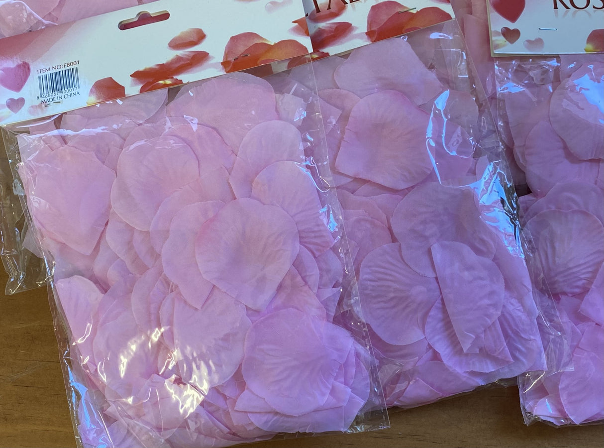 A pack of 900 pink silk rose petals in six bags, perfect for weddings and romantic events, enhancing decor beautifully.