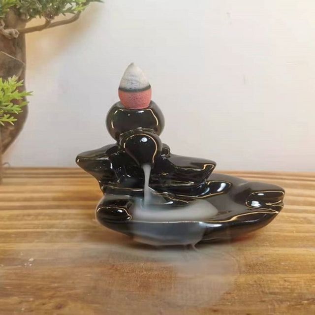 Elegant black ceramic pouring spout incense burner creating a mesmerizing waterfall smoke effect for atmosphere and relaxation.