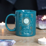 Elegant green ceramic mug featuring The Sun tarot design in white and gold, perfect for coffee, tea, and mystical decor.