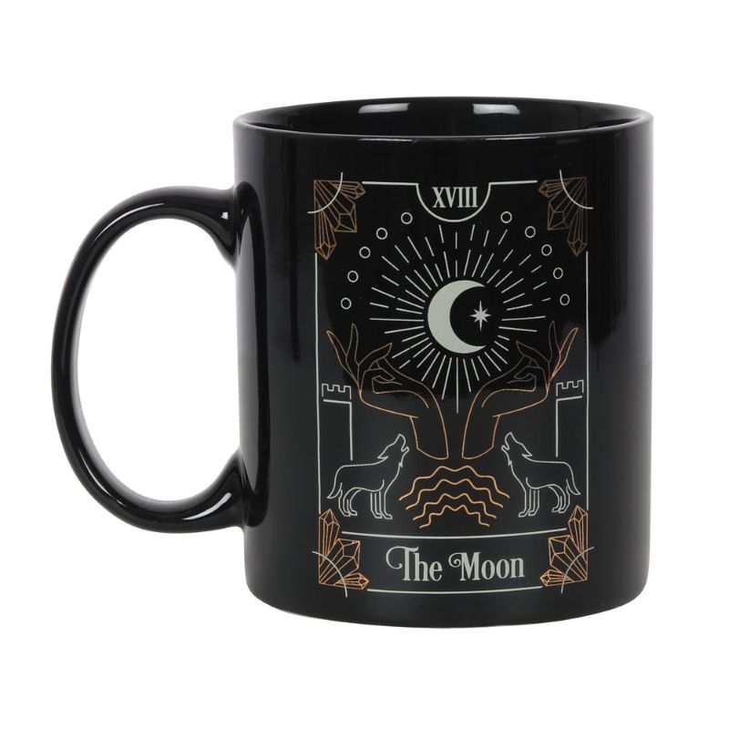 A black ceramic mug featuring 'The Moon' tarot illustration in white and gold foil, perfect for tea or coffee.