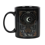A black ceramic mug featuring 'The Moon' tarot illustration in white and gold foil, perfect for tea or coffee.