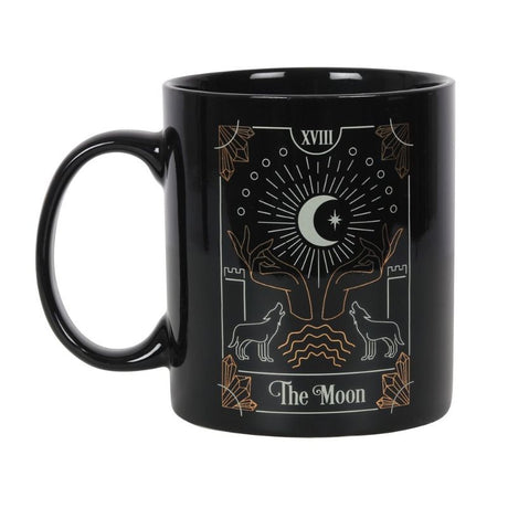 A black ceramic mug featuring 'The Moon' tarot illustration in white and gold foil, perfect for tea or coffee.