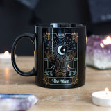 Black ceramic mug featuring a white and gold foil illustration of The Moon, perfect for tea, coffee, or herbal infusions.