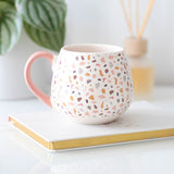 Terrazzo print ceramic mug with pastel speckles, rounded shape, and pink handle, perfect for modern home decor and gifts.