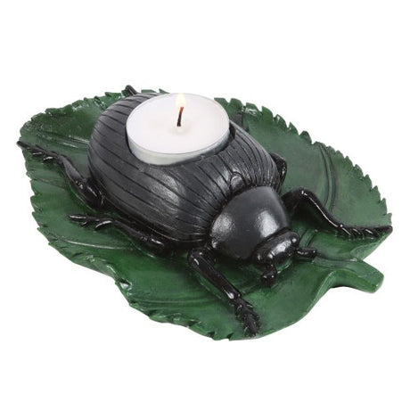 Intricate black beetle tealight holder on a green leaf, adding eerie charm to modern and eclectic decor.