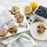 Nordic Ware 12-cup muffin pan made of aluminum with a BPA-free lid for easy storage and transport of baked goods.