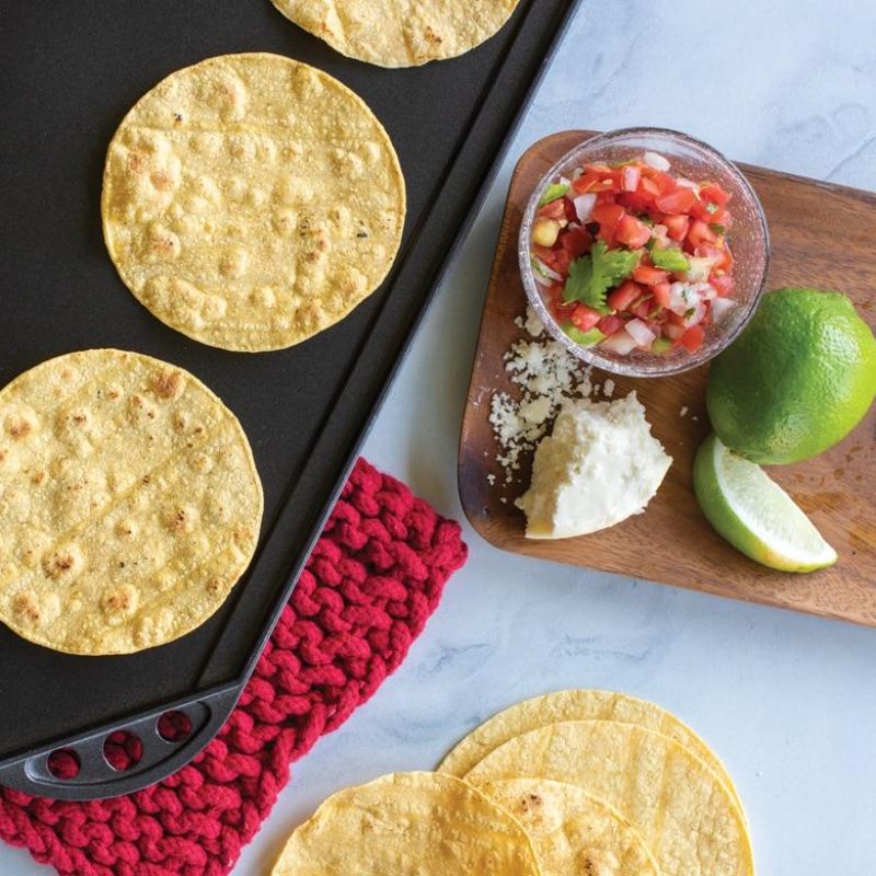 Nordic Ware Two-Burner Reversible Griddle features smooth and ribbed surfaces for versatile cooking, made from durable cast aluminum.