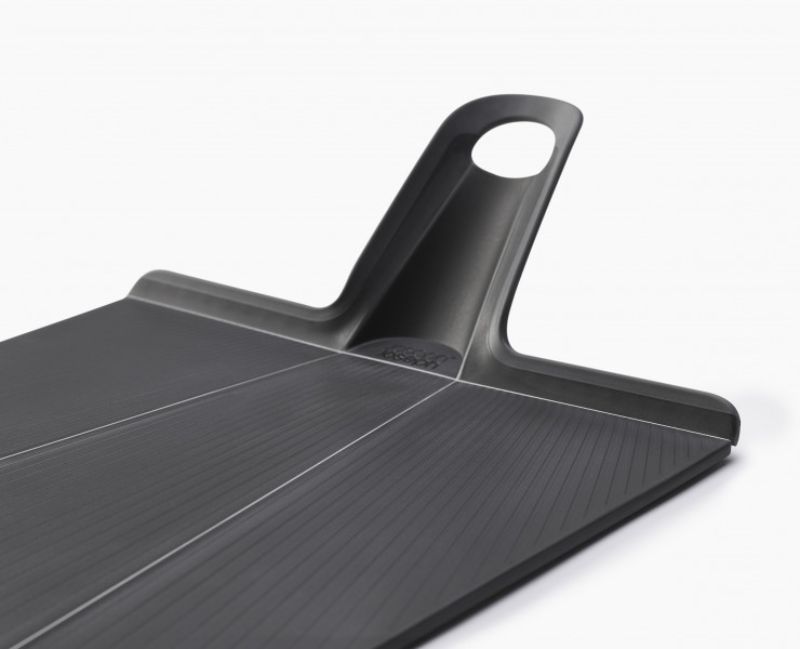 Folding black chopping board with non-slip feet and handle for easy food transfer, ideal for meal prep and cleanup.