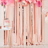 Stunning pink and rose gold streamer backdrop with balloons, perfect for creating a festive photo booth setup.