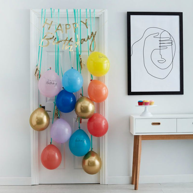 Colorful balloon door kit with gold 'Happy Birthday' bunting, vibrant balloons, and tassels for festive celebrations.