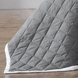 Quilted herringbone bedspread in charcoal with white bound edge, perfect for a queen-sized bed.