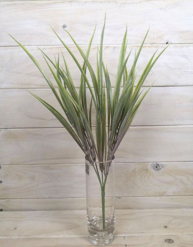 Artificial pink grass bush adding elegance and vibrant color to home decor, perfect for maintenance-free interior enhancement.