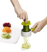 Compact green spiralizer by Joseph Joseph, ideal for creating uniform veggie noodles with sharp blade and safety features.