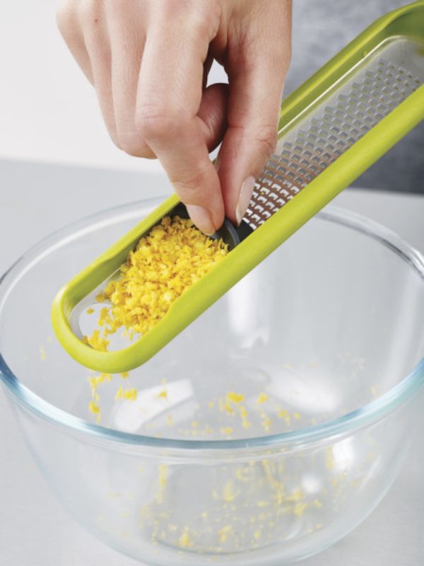 Ergonomic zester with stainless-steel blade, integrated wiper, and protective sheath for easy zesting and cleanup.